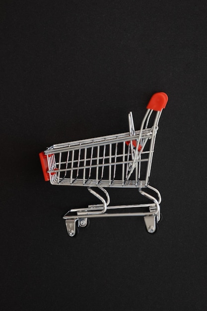 Mini red supermarket trolley on black background Shopping concept