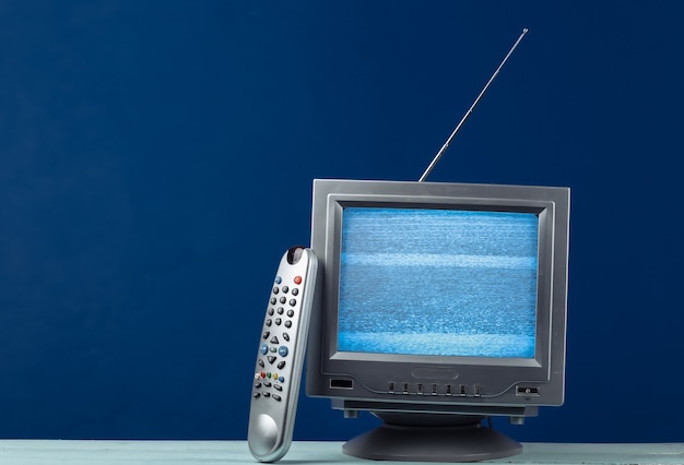 Mini Retro tv antenna receiver on classic blue. Old fashioned TV set with remote.