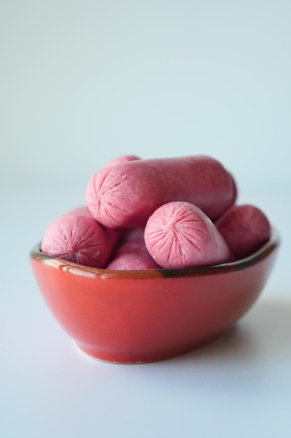 Photo mini sausage in a red color bowl on white