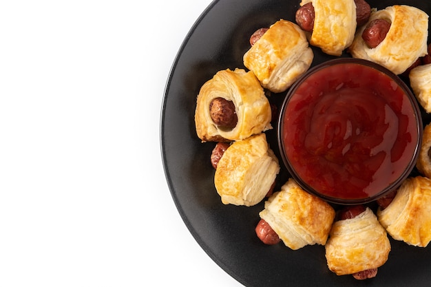 Mini sausages wrapped in puff pastry with ketchup sauce