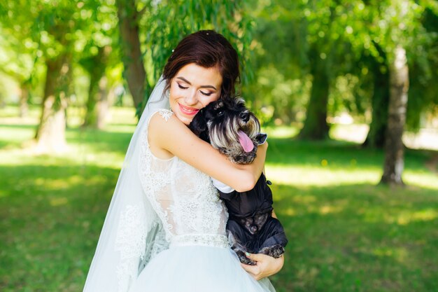 Mini schnauzer op de handen van een mooie bruid in een trouwjurk