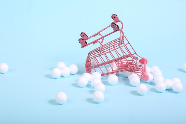 MIni Shopping cart with white balls on a blue background Minimalism shopping still life