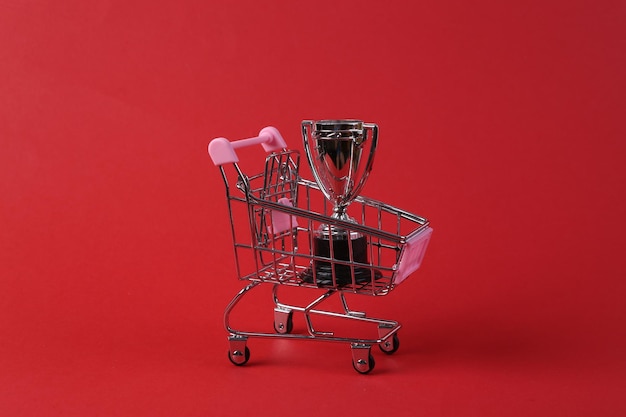 Mini shopping cart with winner cup on red background