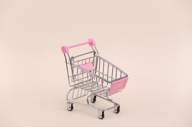 Mini shopping trolley on beige background