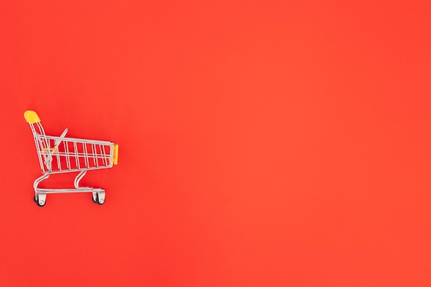 Mini shopping trolley on red background