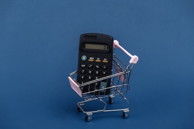 Mini shopping trolley with calculator on classic blue background