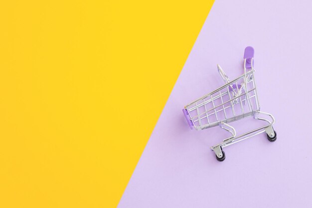 Mini supermarket trolley on violet yellow background