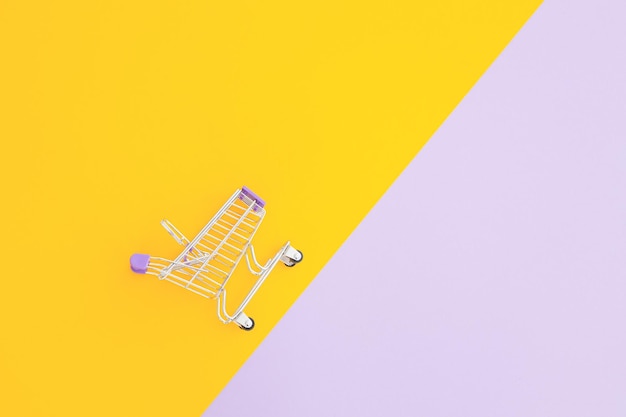 Mini supermarket trolley on violet yellow background