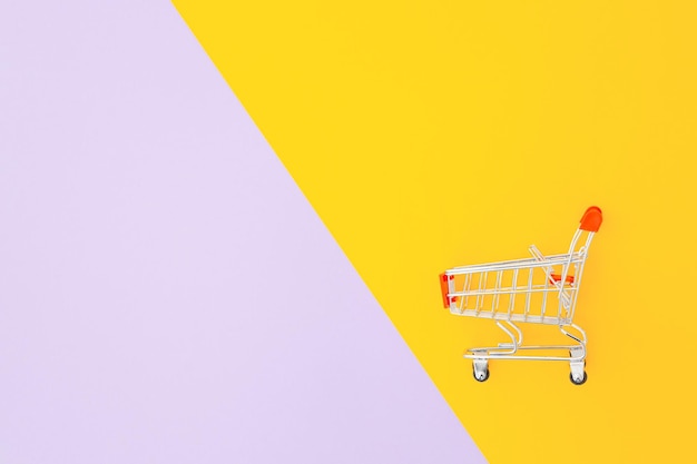 Mini supermarket trolley on violet yellow background