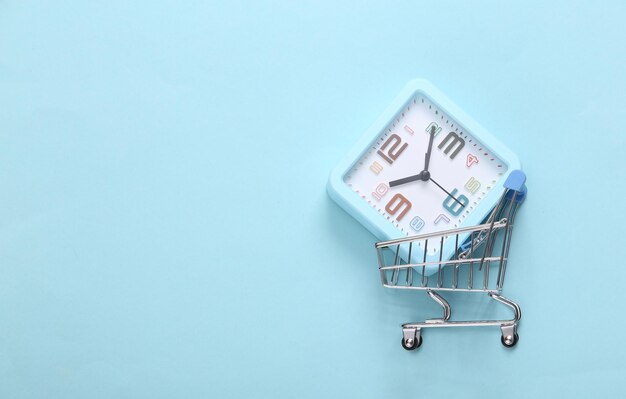 Photo mini supermarket trolley with alarm clock on a blue background