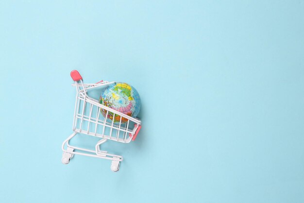 Photo mini supermarket trolley with globe on blue background