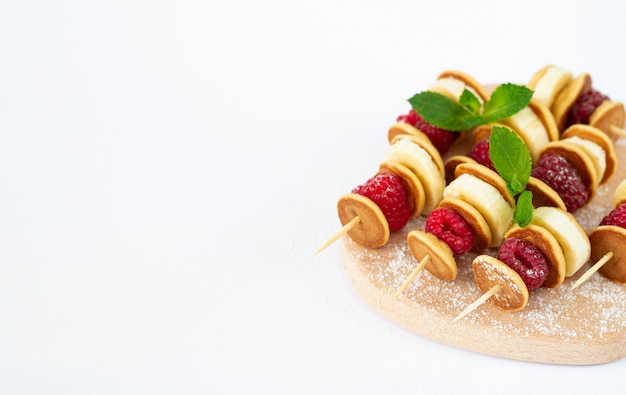 Mini sweet skewers or canape with pancake, raspberry and banana