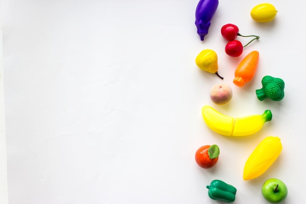 Mini toy vegetables and fruits on white background. Concept of healthy fresh vegetables.