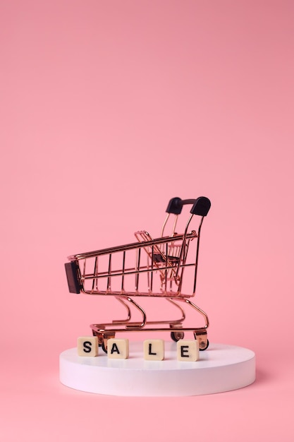 Mini trolley geïsoleerd op roze pastel achtergrond voor winkelen, verkoop en promotie concept