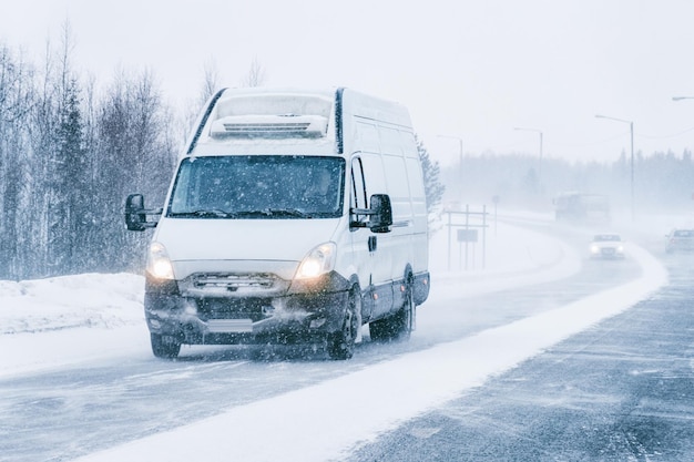 ラップランドのフィンランドの雪に覆われたウィンターロードにあるミニバン。