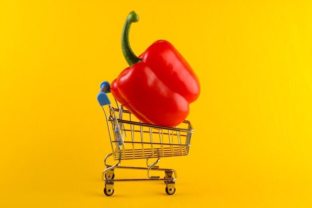 Mini Winkelwagentje met paprika op geel. Supermarkt concept