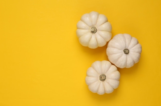 Mini witte pompoenen op gele achtergrond Bovenaanzicht