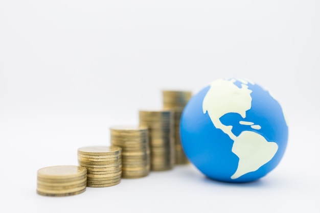 Photo mini world ball with stack of gold coins on white background