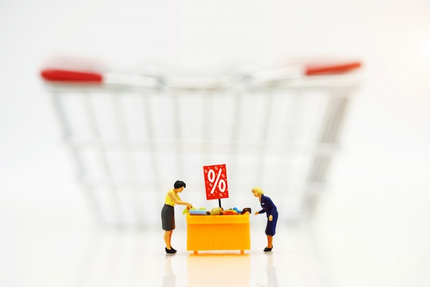 Miniatrue people, Shoppers buy goods on sale with discount tray and shopping cart 