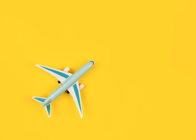 黄色の背景の概念の空の旅のチケット予約の青い飛行機のミニチュア