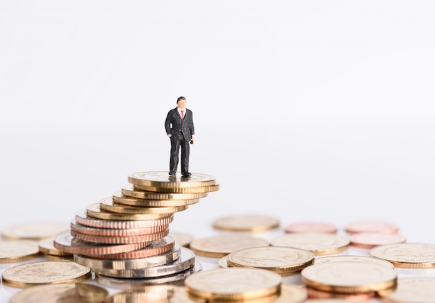 Miniature business people stand on money coins isolated on white, Business successful concept