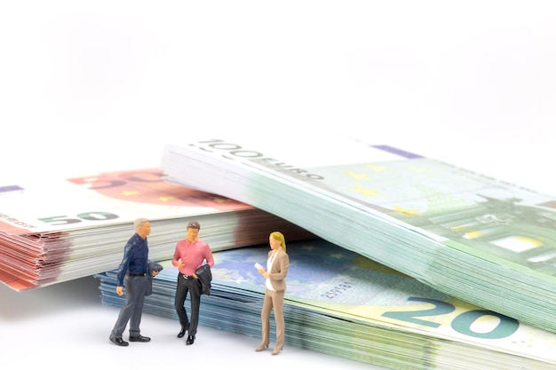 Миниатюрный бизнесмен перемещается по финансовому ландшафту в окружении банкнот евро.