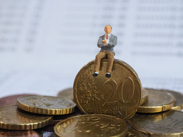 Miniature businessman sit on Euro coins and book bank. Business and idea concept.