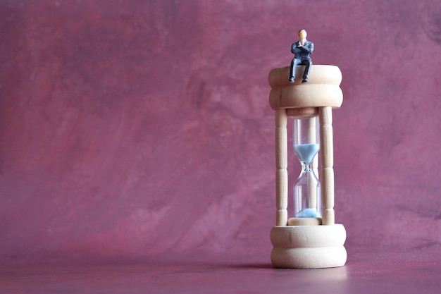 Photo miniature businessman sitting on hourglass with copy space productive work and time management