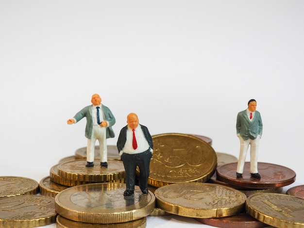 Miniature businessman stand on Euro coins and book bank. Business and idea concept.