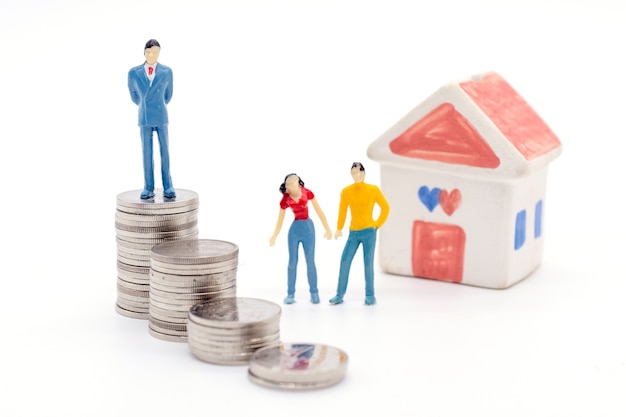 Miniature businessman standing on coins and the house behind. saving and loan concept. 