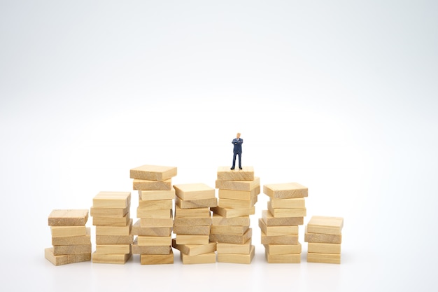 Miniature businessman standing on stack of papers