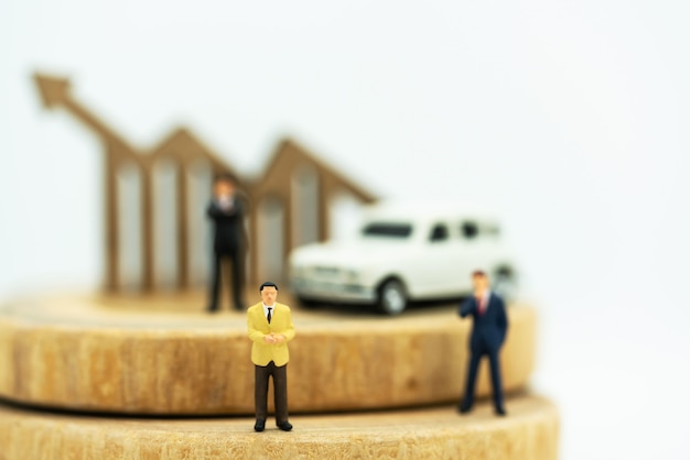 Miniature of Businessmen standing on coins stack with graph and car