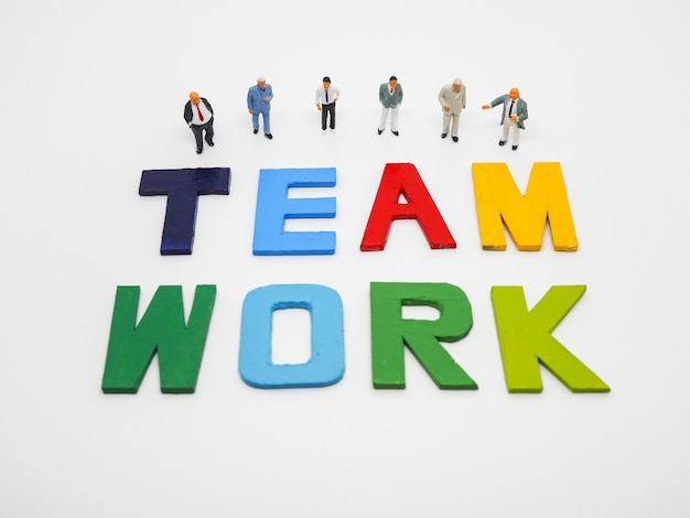 Miniature bussinessman with TEAMWORK word letters on white background