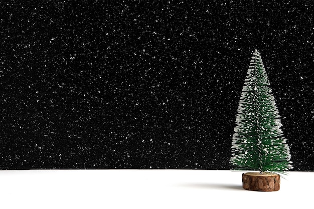 흑백 배경에 눈 조각이 있는 미니어처 크리스마스 트리.