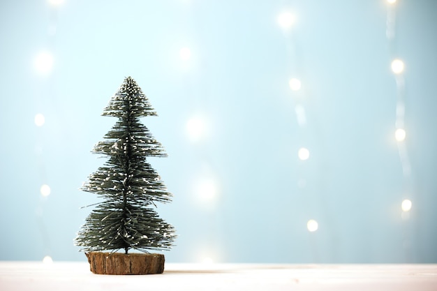 Miniature christmas tree on wooden table over blur bokeh light blue background, Image for Christmas Holiday decorative concept. Minimal concept.