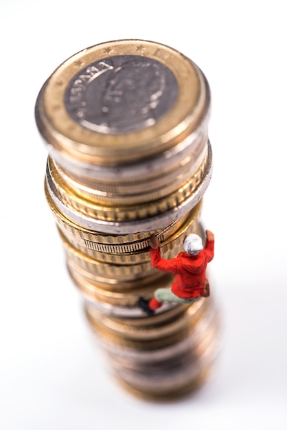 Miniature climber climbing on the stack of coins