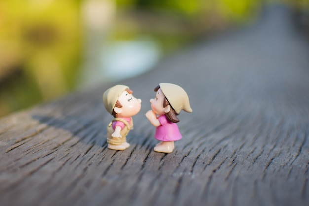 Miniature couple love kiss on wooden ground. 