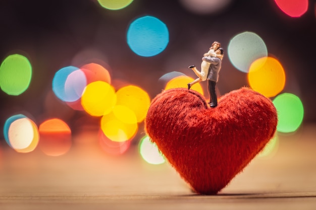 miniature couple standing on red heart