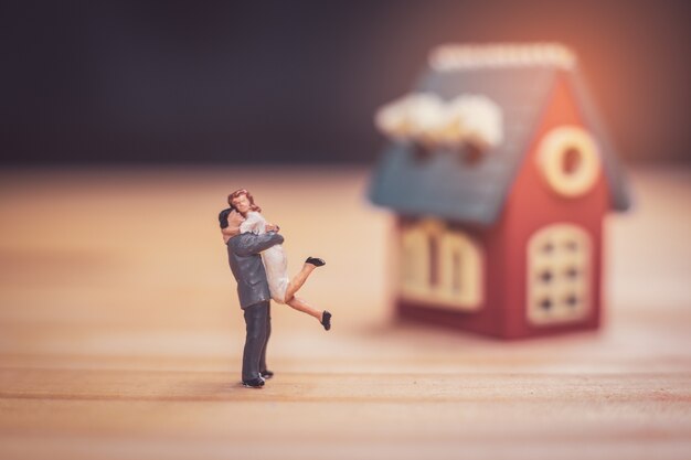 Miniature couple with miniature house  on wooden