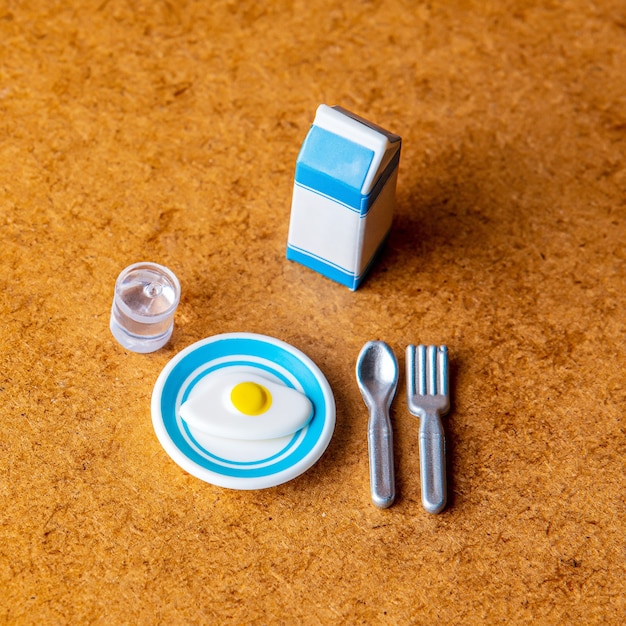 Miniature eggs with milk pack, fork and spoon on wooden table.