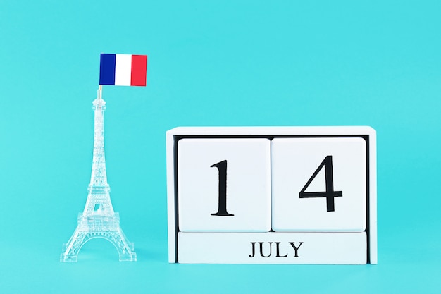 Miniature Eiffel Tower with a French flag and calendar. The concept is July 14, Day of the