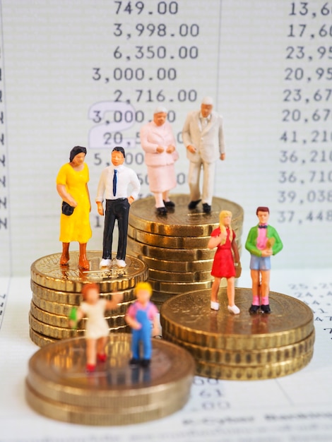 Foto basamento miniatura della famiglia sul mucchio di euro monete e banca del libro.