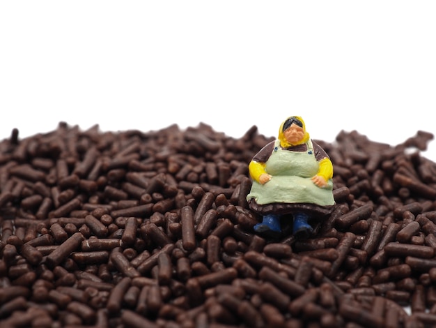 Miniature fat women on chocolate sprinkles on white background. Diet, fat and weight loss concept.