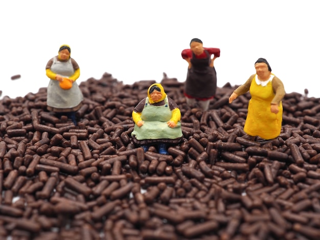 Miniature fat women on chocolate sprinkles on white background. Diet, fat and weight loss concept.