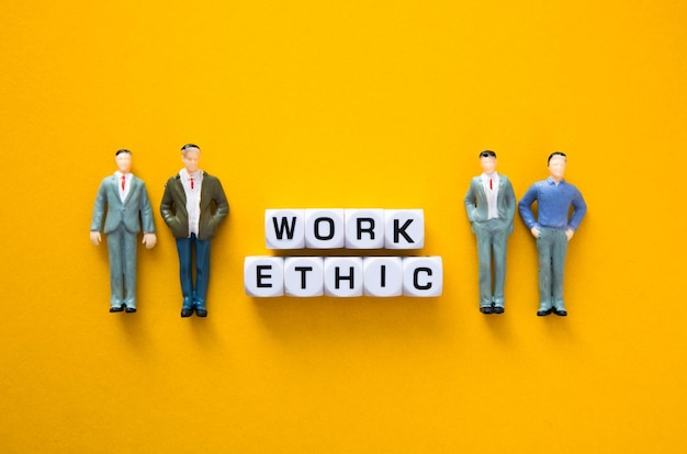 Miniature figure with Work ethic words on yellow background Ethics Business Concept