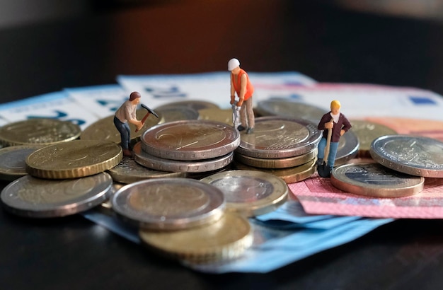 Foto figurine in miniatura di operai che lavorano su un mucchio di soldi