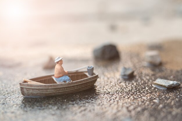 Miniature fishermen are fishing by boat 