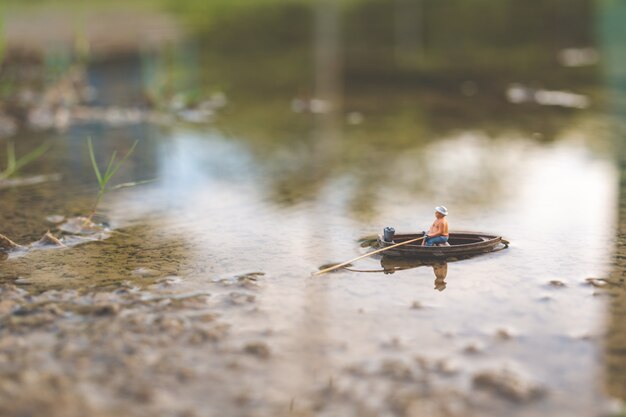 Miniature fishermen are fishing by boat 