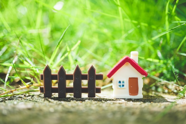 Casa miniatura sul fondo verde della natura usando come concetto della proprietà e della famiglia