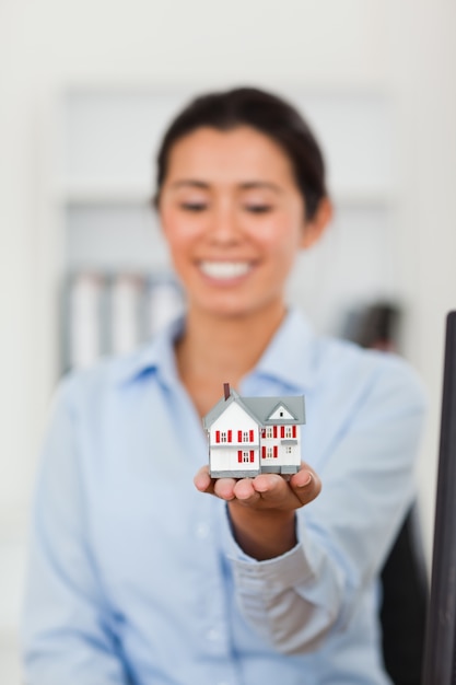 Miniature house held by a good looking woman